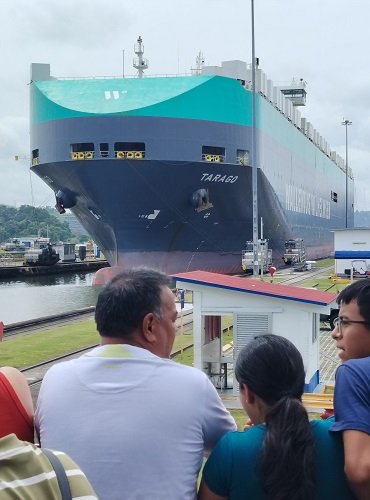 Padre e hijo charlan sobre el buque que están viendo cruzar por el Canal de Panamá